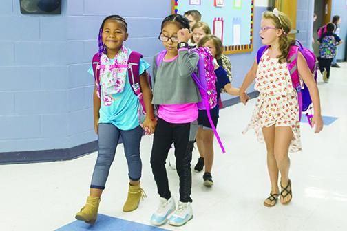 Students walk through the halls holding hands on their first day of school at Interlachen Elementary School last August.