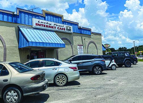 Cars lined up at the entrance to Lucky Pearl Internet Café in Palatka on Tuesday as customers walked inside donning face masks.
