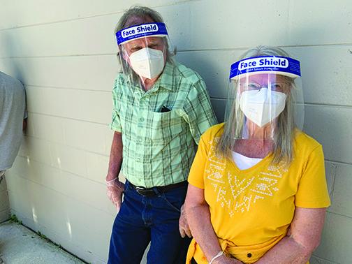William and Emalee Brock wear face shields and masks as they wait in line at Interlachen Community Center for COVID-19 tests.