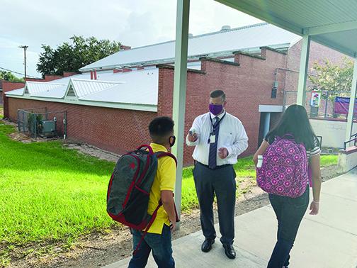Miller Middle School Principal Tim Adams checks students’ temperature as they enter the school Monday morning. 