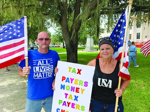 Protesters Mario Fulgium and Jessie Spivey carried flags and signs when they and about 20 people gathered at the Putnam County Courthouse on Tuesday afternoon to protest against the relocation of the Confederate statue.