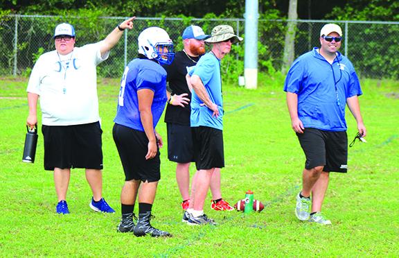 Interlachen High School assistant coach Kim Troiano points to the players where next to go on the IHS practice field, while head coach Matt Yancey, right, smiles. In the middle, from left, are IHS player Giovanni Rosado and assistant coaches Dustin Whitlock and David Criswell. (MARK BLUMENTHAL / Palatka Daily News)