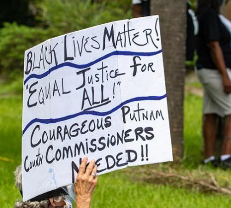 A protester holds a sign during Saturday's event at the Putnam County Government Complex.