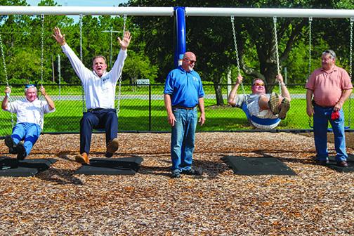 Putnam County commissioners Bill Pickens, Larry Harvey, Buddy Goddard, Jeff Rawls and Terry Turner have some fun on swings at the park.