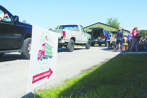 Volunteers distribute food to a line of vehicles during the Farm Share event in May at the Putnam County Fairgrounds in East Palatka.