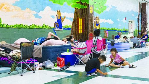 Families rest and mingle in the shelter set up inside Browning-Pearce Elementary School as they wait for a hurricane to pass last year.