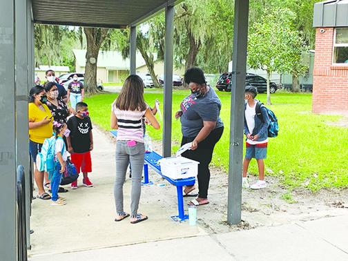 Workers at Middleton-Burney Elementary School assist students and parents last month during the first day of school, which was postponed by two weeks because of COVID-19 concerns.