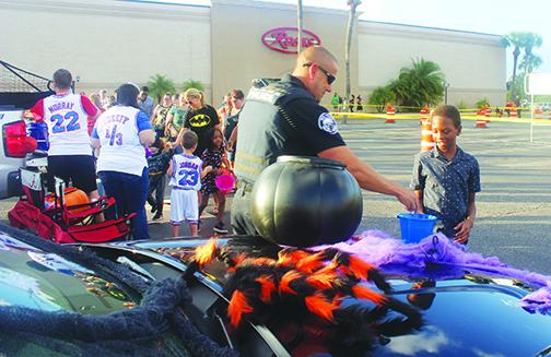 A first responder hands out candy to a line of children at last year’s Trunk or Treat at Palatka Mall.