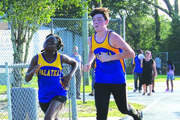 Running alongside boys teammate Caleb Arnold, Palatka High’s Ymira Passmore, left, heads to the finish line to win the girls title. (MARK BLUMENTHAL /Palatka Daily News)