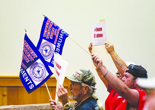 Putnam County residents wave flags during Tuesday’s Putnam County Board of Commissioners meeting advocating for the preservation of and respect for the Confederate monument.