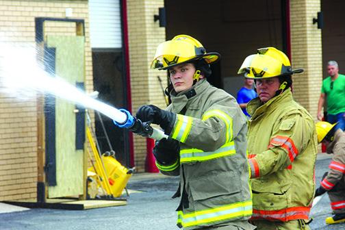Firefighter rookies Cane Willsey, front, and Marcus Wilson advance a hose line and spray it during a two-week training program where new recruits are prepared for job readiness.