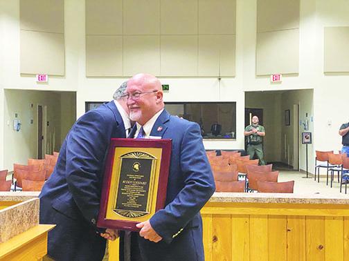 Commissioner Buddy Goddard shakes hands with board Chairman Terry Turner on Tuesday as Goddard is given a plaque honoring his four years of service to Putnam County.