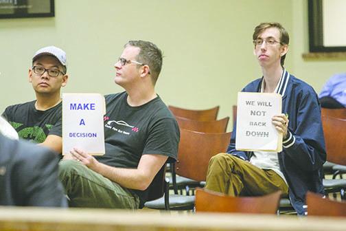 Audience members hold signs in favor of keeping the Confederate statue at the Putnam County Courthouse during a county commission workshop Tuesday.
