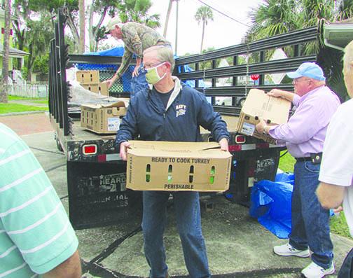 Bob Blake, center, helps Rudy Howard, right and Glenn Thomas, top, unload boxes of frozen turkeys Thursday at the St. Johns River Baptist Association headquarters in Palatka.