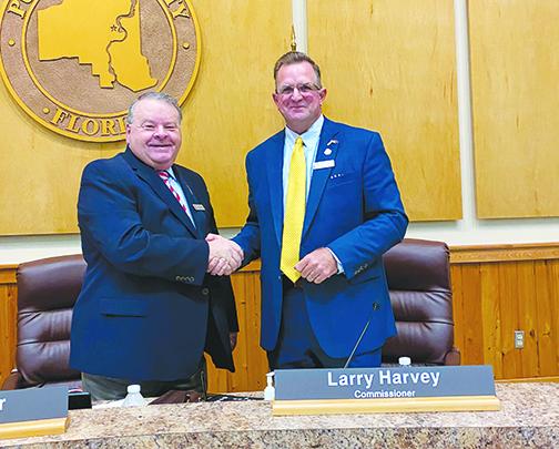 Previous and current Board of County Commissioners chairmen Terry Turner and Larry Harvey shake hands after the transition. 