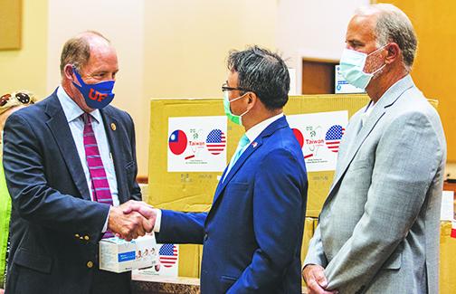 Outgoing U.S. Rep. Ted Yoho, R-Florida, left, shakes hands with David Chien, the director general of the Taipei Economic and Cultural Office, as the former accepts a collection of personal protection equipment from the latter while state Rep. Bobby Payne, R-Palatka, looks on.