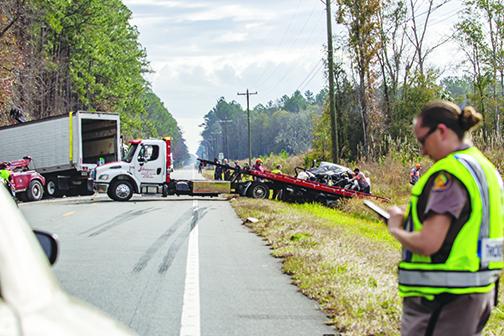 A Florida Highway Patrol trooper inputs data while work crews prepare to tow a pickup truck that was involved in a fatal crash Wednesday morning on State Road 100.