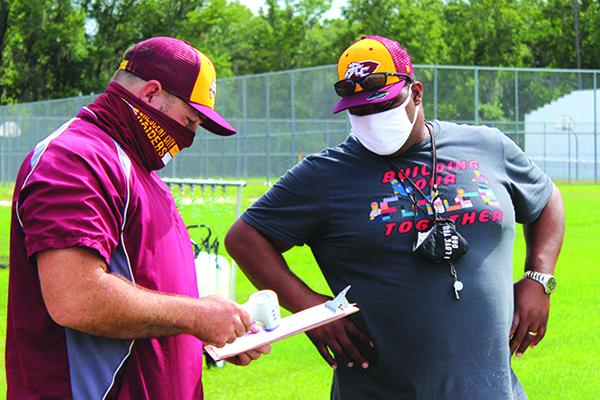 Stacy Cook, right, goes over COVID-19 protocols with athletic director and fellow Crescent City High School assistant football coach Tim Ross on the first day of practice in August. (MARK BLUMENTHAL / Palatka Daily News)