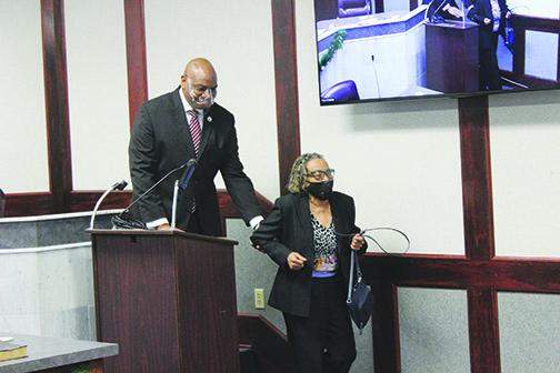 City Commissioner Willie Jones helps outgoing Commissioner Mary Lawson Brown off the dais Monday night as he’s sworn in to replace her.