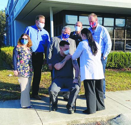 A Putnam County first responder receives the COVID vaccine Monday at the Florida Department of Health in Putnam County while local officials watch.