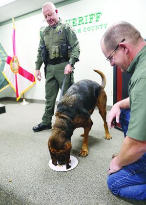 K9 Putnam eats a treat in front of Putnam County Sheriff Gator DeLoach, right, and handler Sgt. Emmett Merritt. Putnam, 9, is retiring after a career filled with finding people, drugs and stolen items in this and surrounding counties.