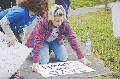 A member of the Melrose Patriots makes a sign Friday in favor of keeping Melrose Elementary School open.