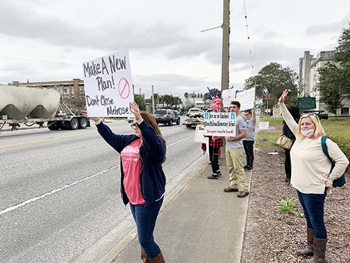 Melrose residents protesting the potential closure of Melrose Elementary School wave to traffic in front of the school district headquarters Tuesday afternoon.