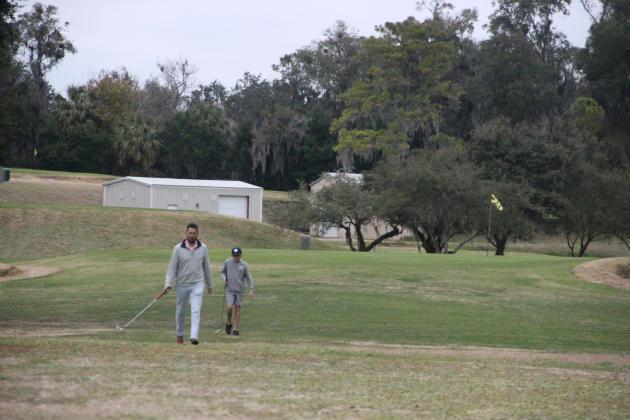 Mike Meredith and his son, Luke, walk the greens at the Palatka Municipal Golf Course during the late afternoon on Tuesday. (MARK BLUMENTHAL / Palatka Daily News)