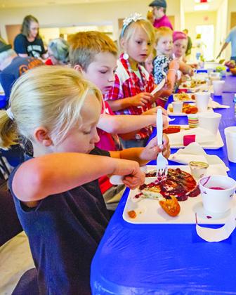 Children feast on blueberry pancakes and sausage at last year’s festival.