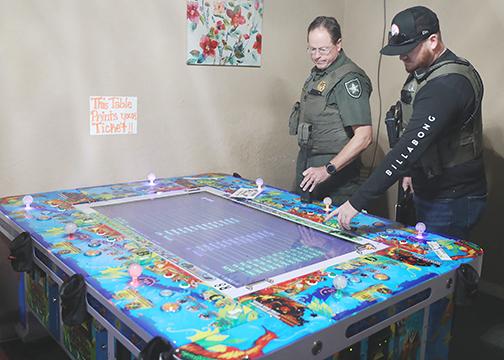 Putnam County Sheriff’s Office deputies inspect a gaming machine Friday at a local internet café before arrests are made there and at another establishment.