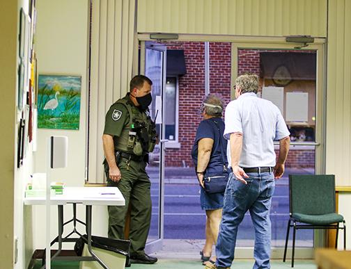 A Putnam County Sheriff’s Office deputy holds the door for Crescent City residents Diane Sykes and R.L. Hall as they leave the commission meeting Wednesday immediately after officials voted to abolish the police department.