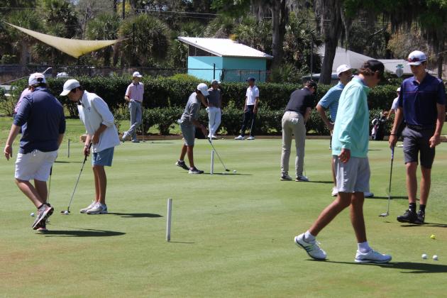 Several golfers practice putting prior to starting their first round. (MARK BLUMENTHAL / Palatka Daily News)