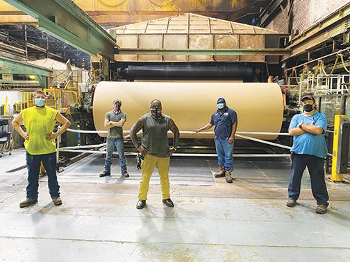 Georgia-Pacific employees stand in front of a kraft paper machine, which produces the paper for Amazon’s recyclable envelopes, a service the Palatka plant’s manager said has cemented the company even deeper in Putnam County.