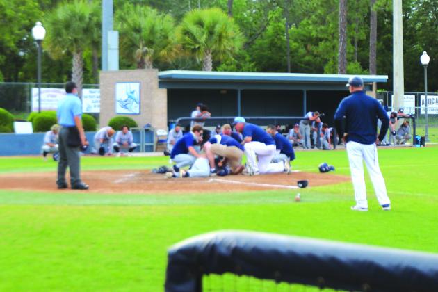 St. Johns River State and Santa Fe coaches and personnel tend to Santa Fe College’s Santiago Garavito after he was hit by a pitch during Wednesday’s game. The game was stopped as Garavito was taken away by ambulance. (MARK BLUMENTHAL / Palatka Daily News)