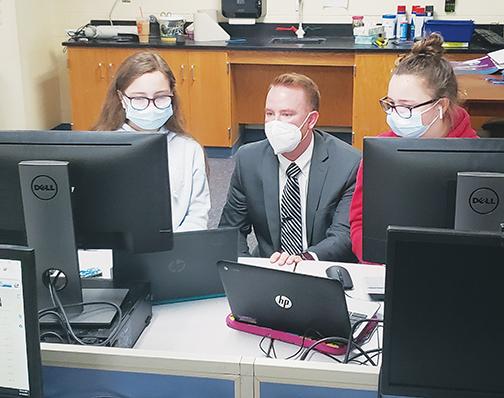 Michael Helms, STEM specialist for the Putnam County School District, talks with Riley Blackmer, left, and Reagan Blackmer during an AI workshop at Q.I. Roberts Junior-Senior High School.