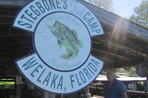 Stegbone's owner Jim Stege talks about the history of the fish camp underneath a Stegbone's sign on the dock.