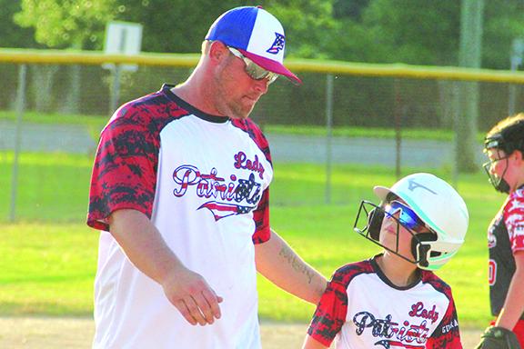 Brandon Zurn, left, talks to one of his players with the Palatka Lady Patriots, a 10-and-under softball team during a game this week. (ANTHONY RICHARDS / Palatka Daily News)