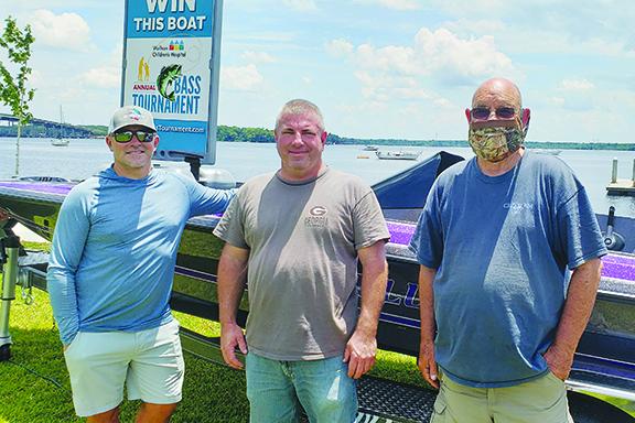 Competitor Jason Caldwell, left, stands alongside tournament co-director Mike Bach and Pete Allen on Wednesday in front of a boat that will be given away as part of the Wolfson event. (WAYNE SMITH / Palatka Daily News)