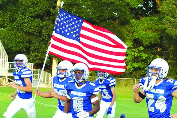 Interlachen High spring football players come out waving the American flag before kickoff last Friday night against Trenton High, a game the Rams lost, 38-18. (ANTHONY RICHARDS / Palatka Daily News)