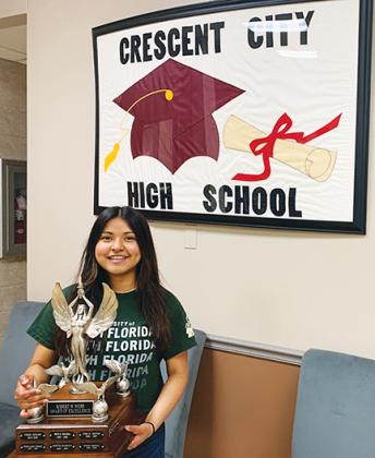 Robert W. Webb Award of Excellence winner Lizbeth Espinoza stands in front of Crescent City High School’s new sign Thursday as she holds the award, which she won earlier this month at the school district’s Top Scholars ceremony.