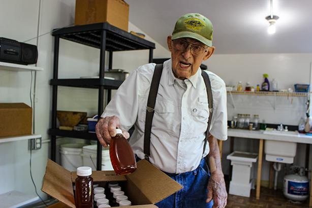 Florahome resident and beekeeper Ray Merrill takes out boxes of jarred honey that he bottled from the honeybees he keeps in his backyard.