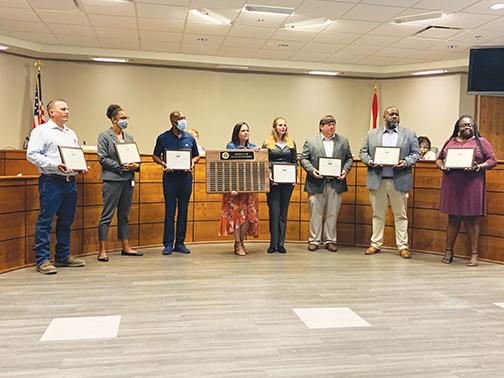 Scott Brauman, Sharice Williams, Wade Dallas, Heather Hoffman, Matt Buckles, Aaron Hall and Trinisha Austin hold their Product of Putnam awards at Tuesday’s Putnam County School District board meeting as Community Relations Director Ashley McCool, center, holds the plaque on which their names are etched.