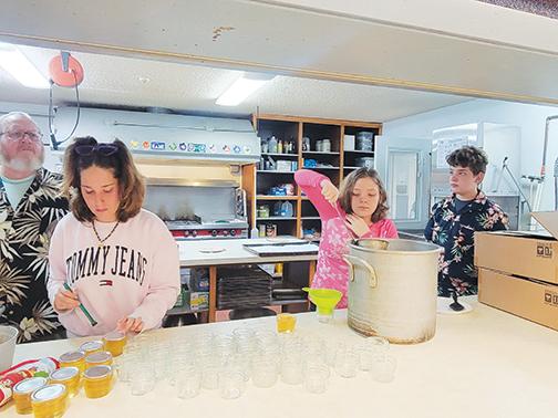 Peniel Baptist Academy eighth graders Lilly Zumbar, Haylie MacGibbon and Hayden MacGibbon make jam May 24 under the supervision of Robert Massey, who teaches social sciences at the school.