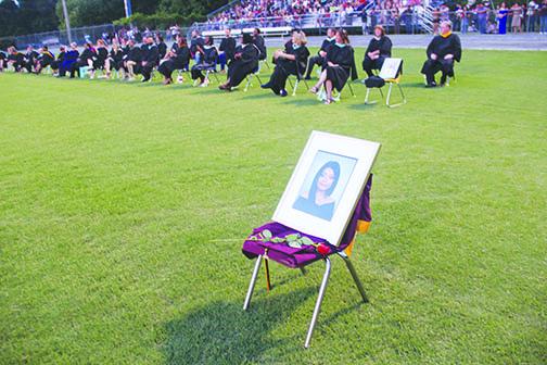  Empty chairs with portraits of Leslie Vazquez, front, and coach Stacy Cook are displayed on the field with Crescent City graduates Thursday night.