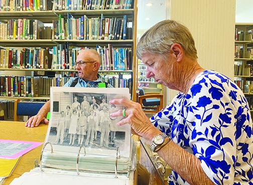 Former Bostwick Library Branch Manager Claudia Wilkinson looks over photos of the building as her husband, Charlie Wilkinson, recalls memories from when he went to school in the same building during the 1940s.