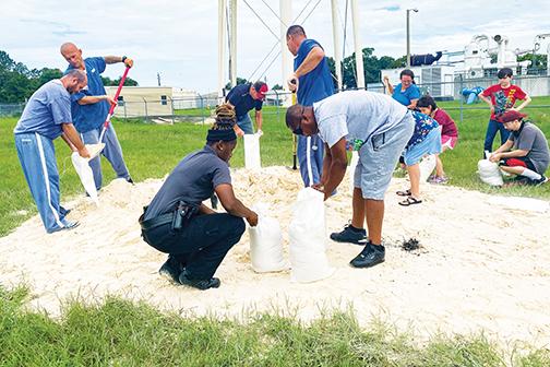 Putnam County officials, residents and members of the county’s inmate work crew fill bags of sand Tuesday at the East Palatka Community Park.