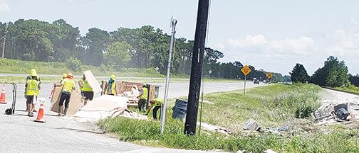 Workers pick up drywall near U.S. 17 North on Friday near where an Amtrak passenger train struck a tractor-trailer. 