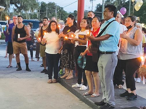 A small choir sings during a vigil service for Mark Anthony Arbelo Jr., held at his father’s business on Friday night in Crescent City.