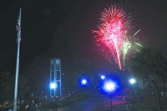 Fireworks light up the night sky Sunday at the Palatka riverfront behind the clock tower and American flag.