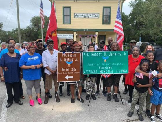 Friends and relatives of Medal of Honor winner Robert H. Jenkins Jr. stand behind signs dedicated in his honor Saturday during Interlachen’s Independence Day celebration.